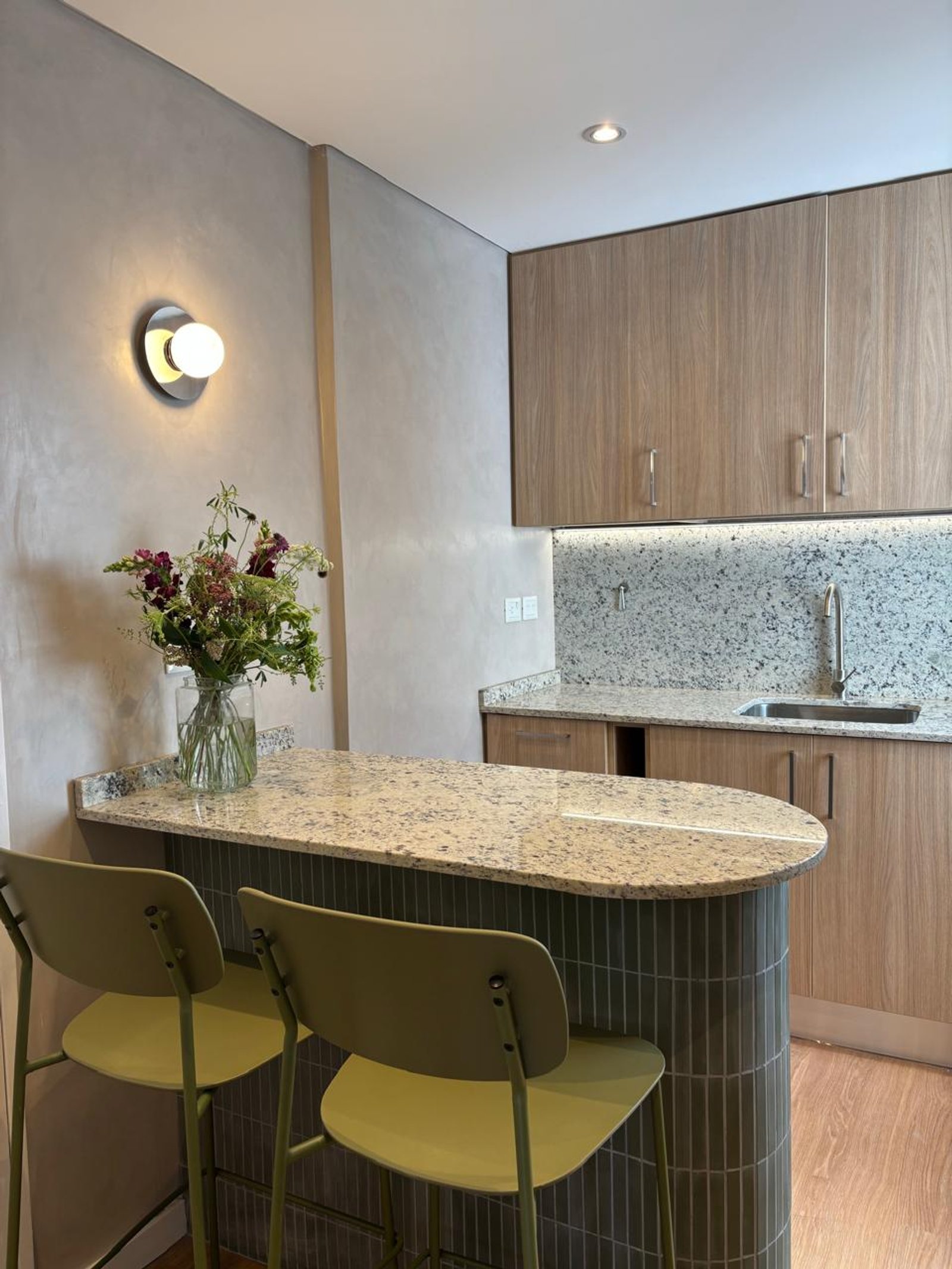 Cocina moderna con barra curva y paredes texturizadas — proyecto French, por cromo., en Recoleta